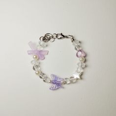 a bracelet with beads, charms and bows is shown on a white surface in front of a plain background