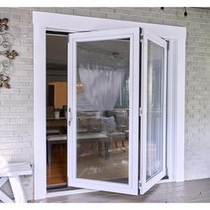 an open sliding glass door on the outside of a house with patio furniture and white curtains