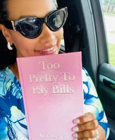 a woman sitting in the back seat of a car holding up a pink book that says too pretty to pay bills