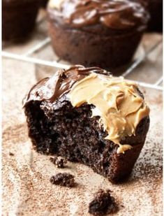 chocolate cupcakes with peanut butter frosting on a cooling rack and one half eaten