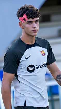 a man with a pink bow in his hair wearing a black and white soccer jersey