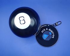 a black and white keychain sitting next to a ball on a blue surface