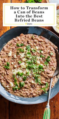 a bowl filled with beans and greens on top of a wooden table next to a fork