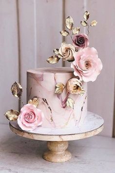 a pink marbled cake decorated with gold leaves and flowers