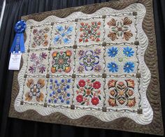 a quilted wall hanging on the side of a black curtain with a blue ribbon around it