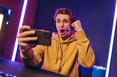 a man with headphones on taking a selfie in front of a computer screen