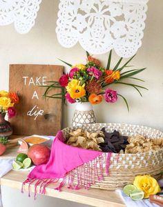 a table topped with flowers and fruit next to a sign that says take a dip