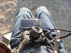 a person sitting on the ground with a camera and cell phone in their lap top