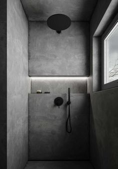 a bathroom with concrete walls and flooring is shown in black and white, as well as a shower head