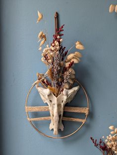 an animal's head is mounted on the wall next to dried flowers