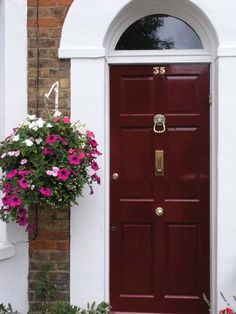 a red door with white trim and pink flowers in the planter on either side