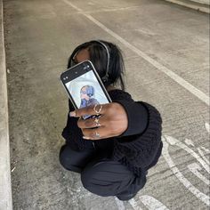 a woman kneeling down holding up a cell phone to take a selfie with her hand