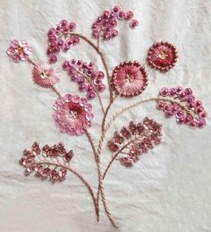 some pink flowers are sitting on a white table cloth and it looks like they have been made from glass beads