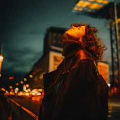 a woman looking up at the sky with her eyes closed on a city street corner