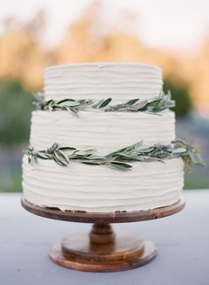 a white wedding cake with greenery on top