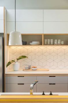 a kitchen with white cabinets and counter tops next to a refrigerator freezer filled with dishes