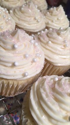 some cupcakes with white frosting and sprinkles on them are sitting on a cooling rack