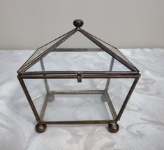 a glass and metal box sitting on top of a white tablecloth covered flooring