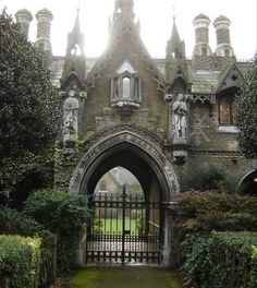 an old building with statues on the front and gated in lawn area next to it