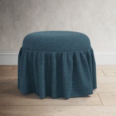 a blue ottoman cover sitting on top of a wooden floor next to a white wall