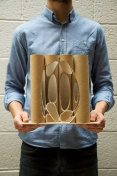 a man holding a cardboard box with spoons in it's center and two hands