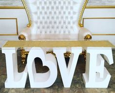 a love bench sitting on top of a tiled floor next to a white and gold chair