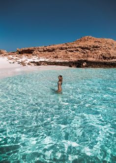 a woman standing in the middle of clear blue water