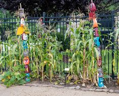 the garden is filled with colorful scarecrows, corn stalks and fire hydrants