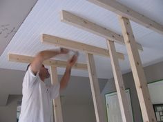 a man standing on top of a hard wood floor next to a white ceiling with beams