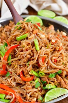 a bowl filled with noodles and vegetables on top of a wooden table