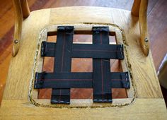 a wooden chair with black and red stitching on it's seat padding