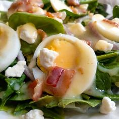 a salad with hard boiled eggs, bacon and spinach leaves on the side is ready to be eaten