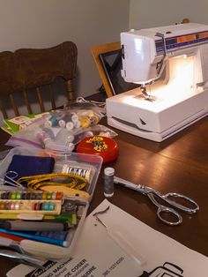 a sewing machine sitting on top of a wooden table next to scissors and other crafting supplies