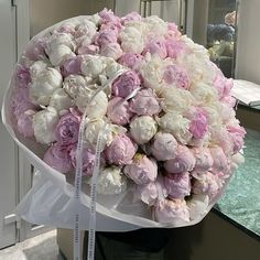 a large bouquet of pink and white flowers on a counter in front of a mirror