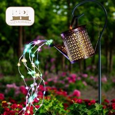 a teapot with lights is in the middle of some flowers