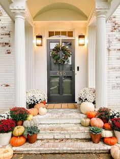 a front porch decorated for fall with pumpkins and gourds