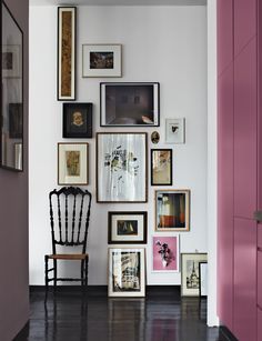 a chair sitting in front of a wall with pictures on it's sides and framed photos on the walls