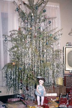 a small christmas tree in the corner of a living room with presents on the floor