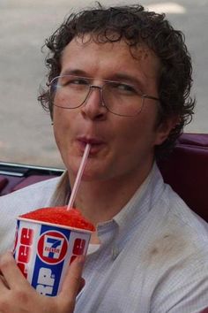 a man in glasses drinking from a cup with a straw sticking out of it's mouth