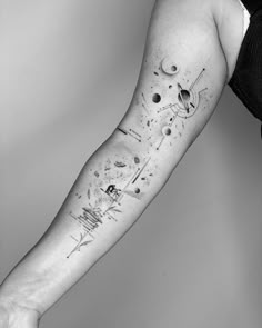 a person with a black and white tattoo on their arm that has planets in it