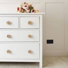 a white chest of drawers with flowers on top