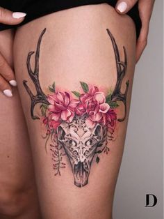 a woman's thigh with flowers on it and a deer skull in the middle