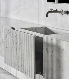 a bathroom with marble walls and flooring next to a white sink under a faucet