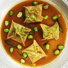 some dumplings are in a brown broth with peas