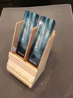 two books are placed in a wooden holder on a table top with metal grates