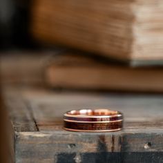 a wooden ring sitting on top of a table next to a stack of book pages