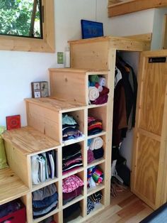 an image of a closet with clothes on the bottom shelf and stairs to the top