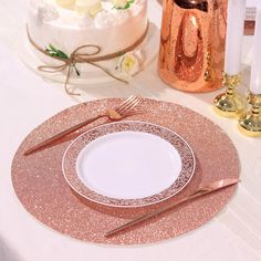 a table set for two with gold and white plates, silverware and candles on it