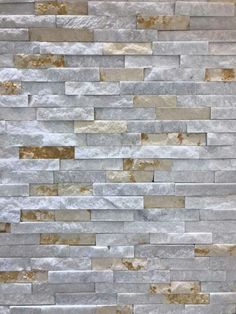 a white and brown brick wall that is made out of various types of stone tiles