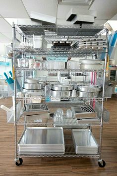 a metal shelf filled with pots and pans on top of a hard wood floor